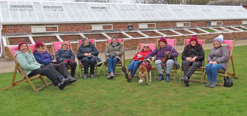 Nine ladies sit in deckchairs wrapped in winter woollies