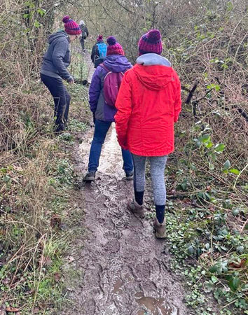 Three women walk along a very muddy path