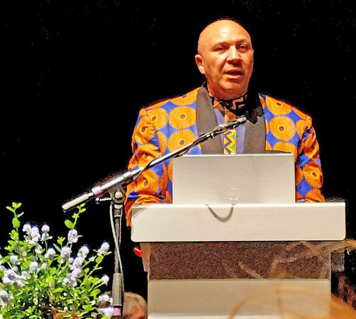 A man in a bright jacket stands at a podium