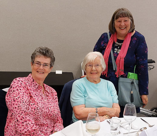 Three ladies at a dinner table pose for the camera