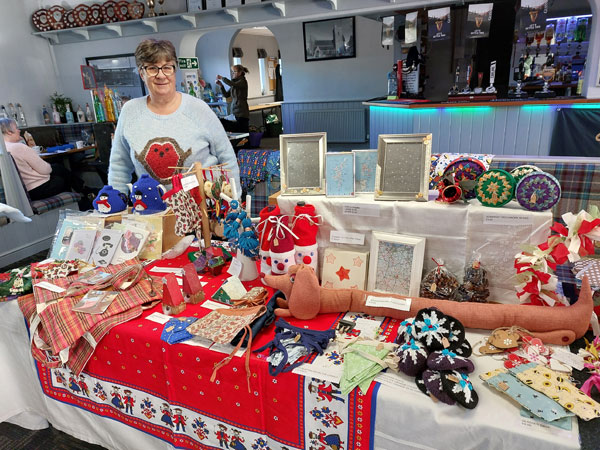 A lady stands behind a stall of handmade crafts