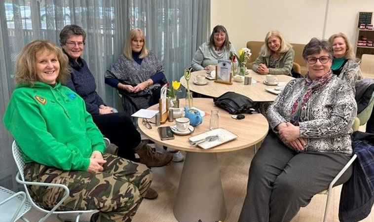 Seven ladies sit around tables after coffee