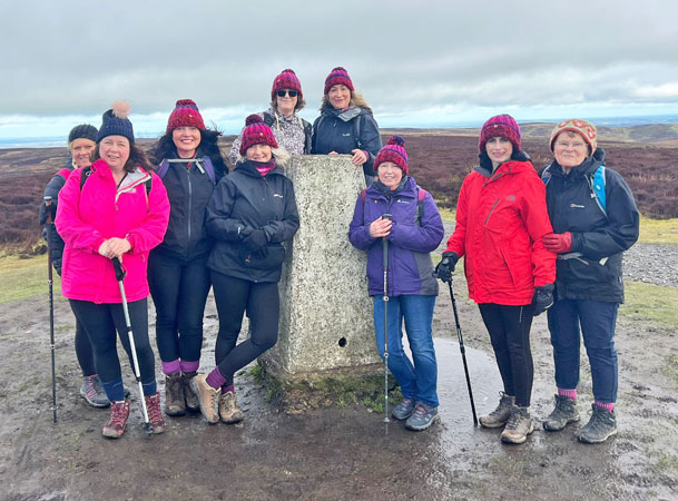 Nine ladies well wrapped up by a stone pillar on top of the hill