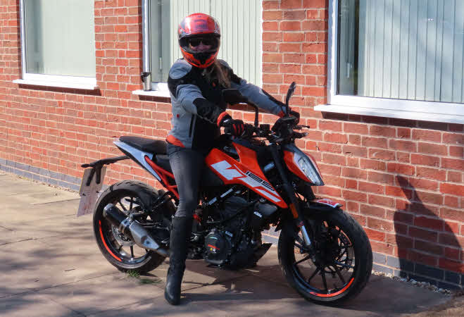 Mandy on her black and red motorbike wearing her matching black and red leathers and helmet.